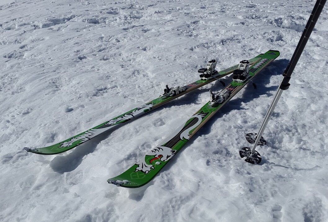 Zwei grüne Skier mit Skistock im Schnee