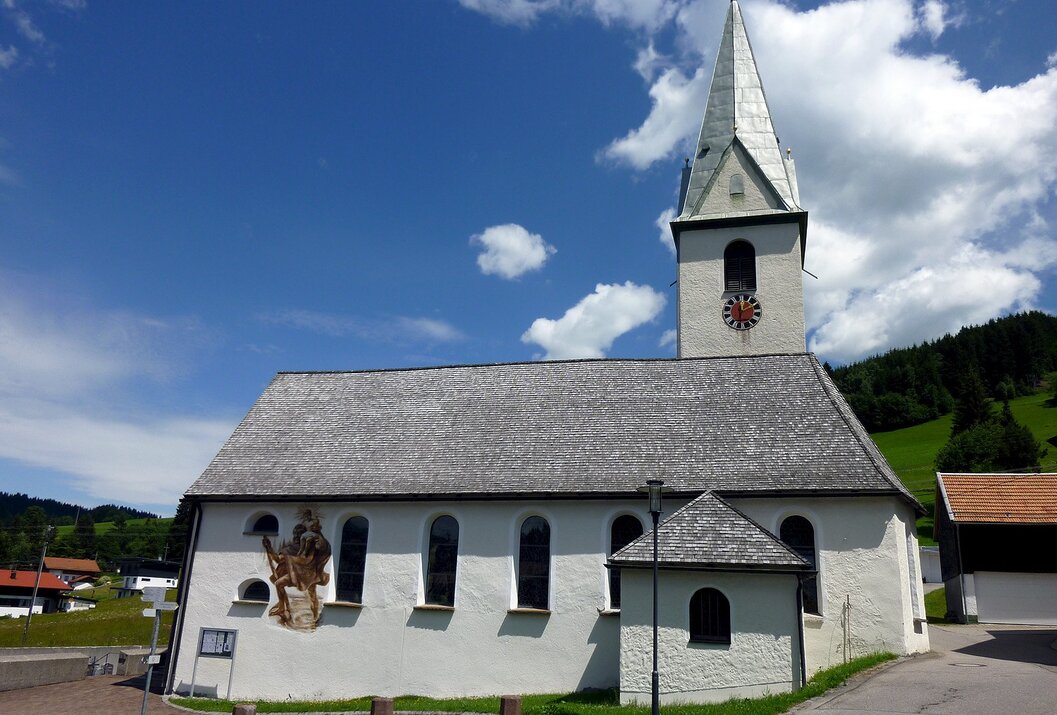 White church with a tall tower and mural