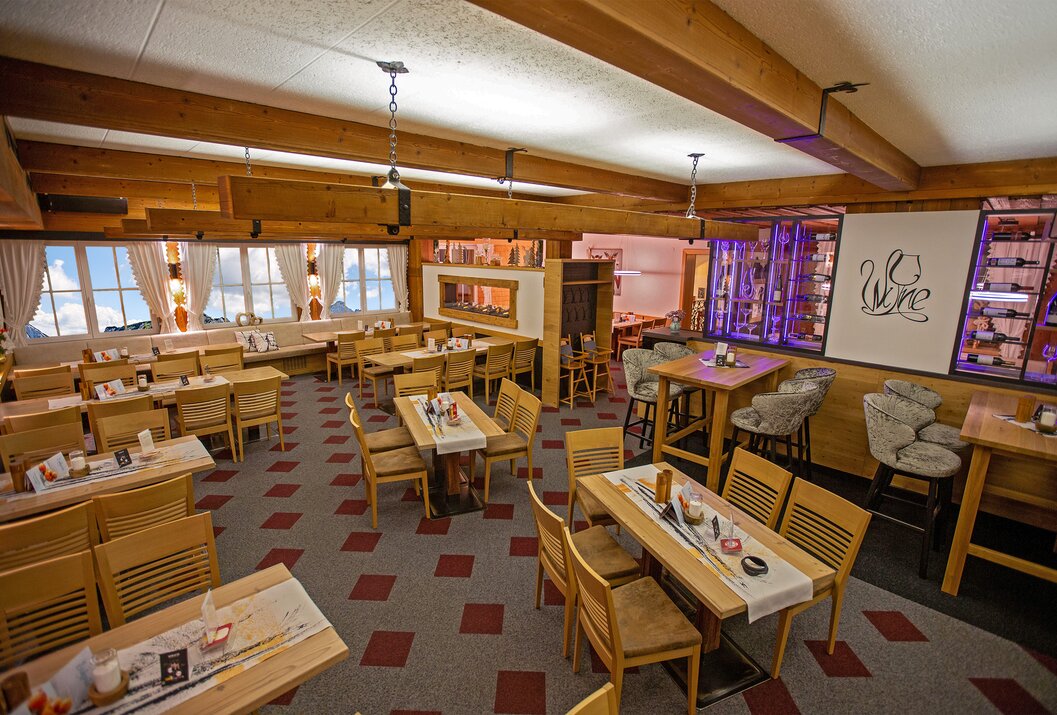 Alpenländischer Gastraum mit Holztischen und Bar