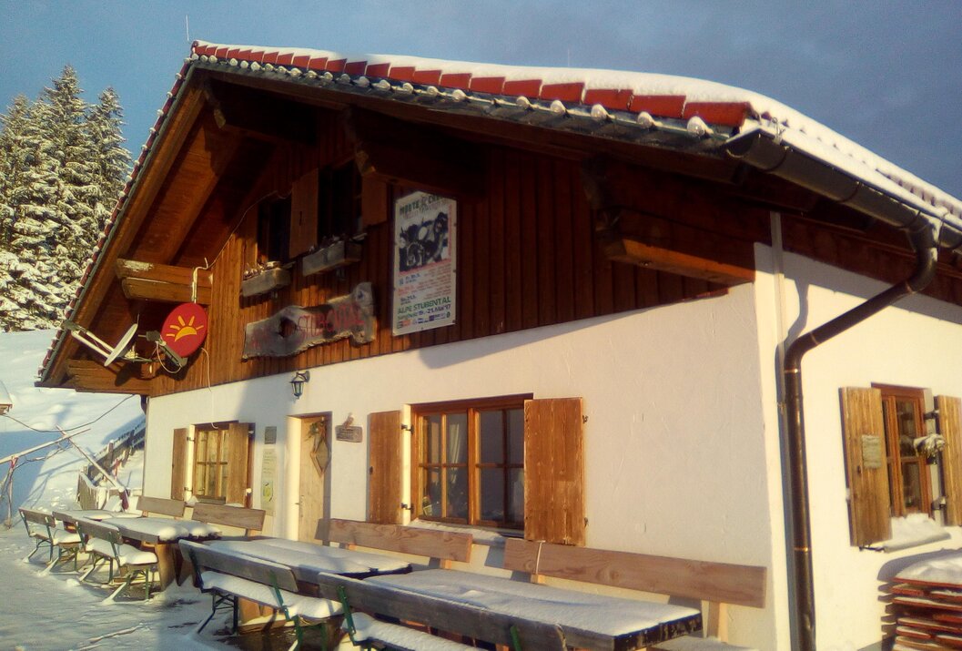 Verschneite Berghütte mit sonniger Außenterrasse