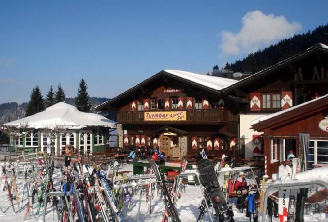 Verschneite Skihütte mit vielen Skiern im Winter
