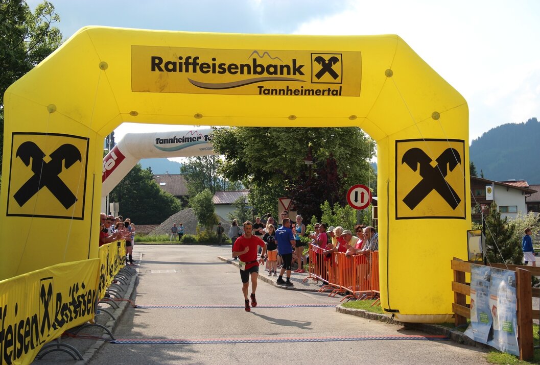 Runner crosses finish line in front of large yellow gate