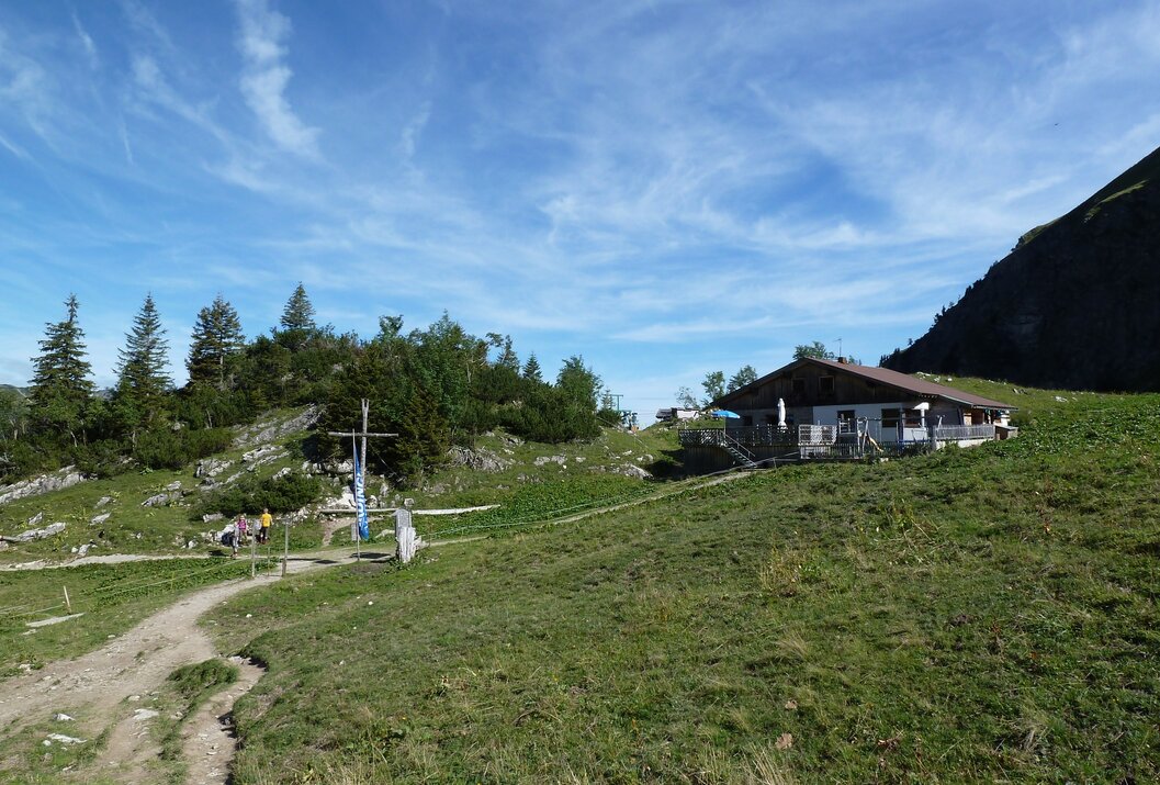 Mountain hut on green alpine pasture under blue sky