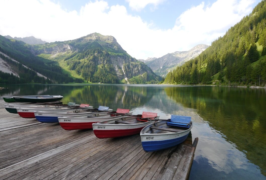 Rowboats at the wooden jetty in front of an idyllic mountain lake