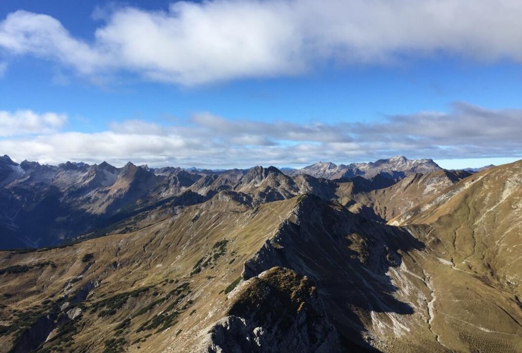 Vast mountain range under a blue sky with clouds